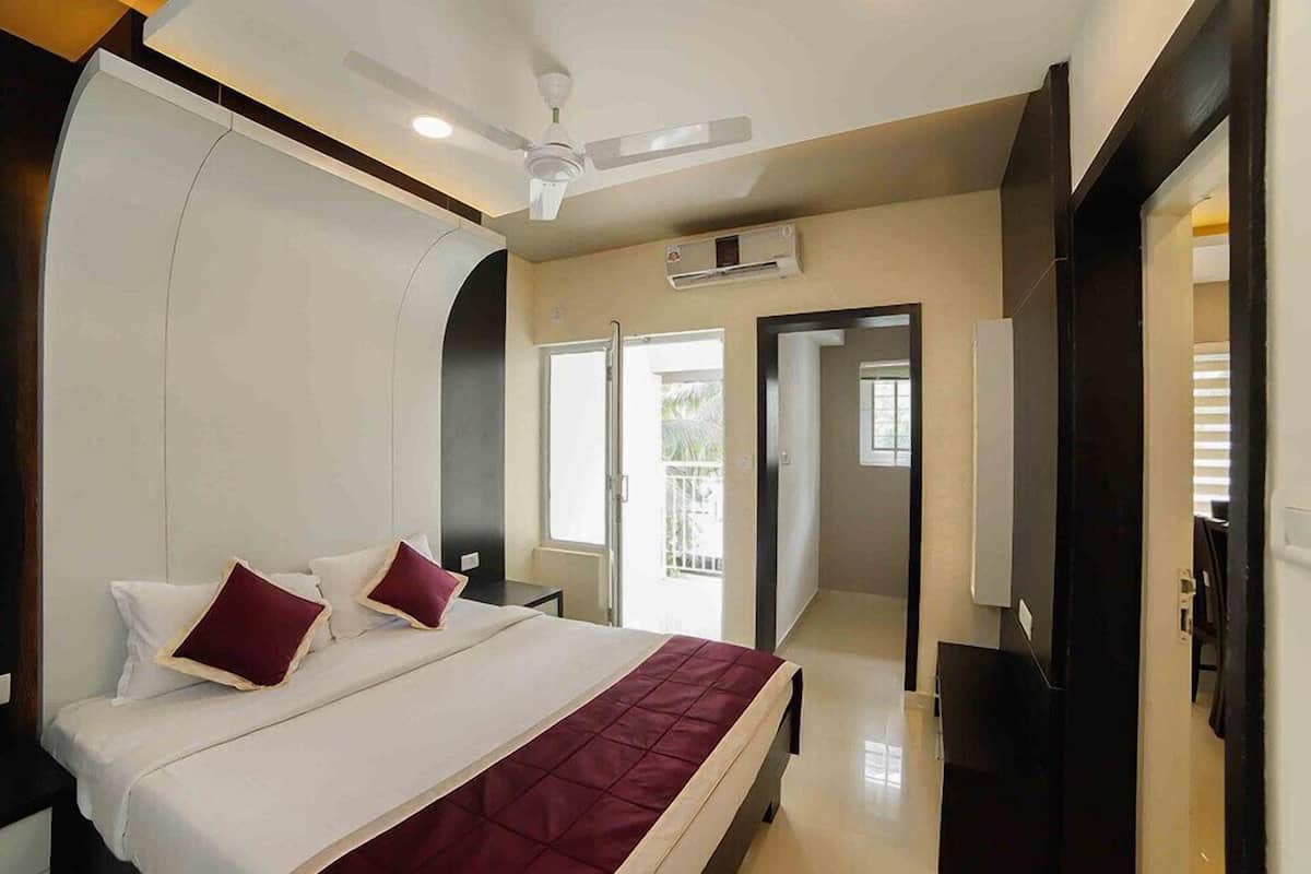 A hotel room with a bed, a ceiling fan, an air conditioning unit, and a view of the outside.