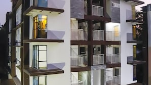 A multi-story residential building with balconies, a car parked in the driveway, and a small garden area. - Ambalath Maple Leaves - Hostel (Chavakkad)
