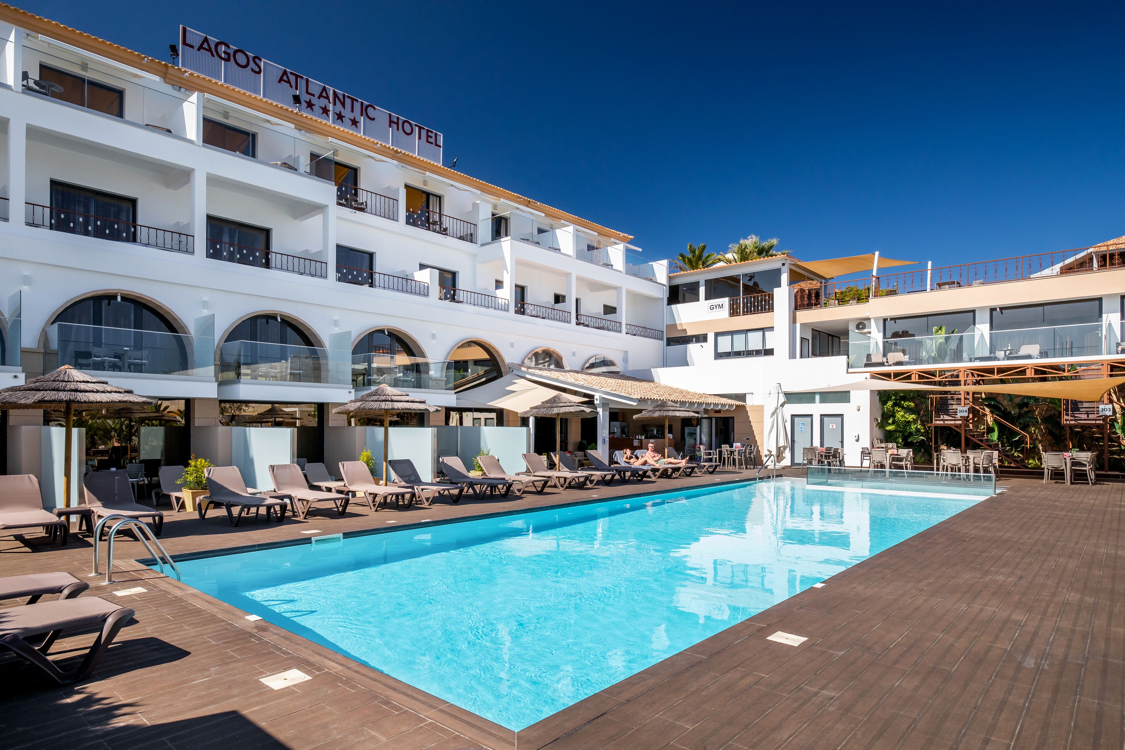 A hotel with a swimming pool, sun loungers, and a gym.