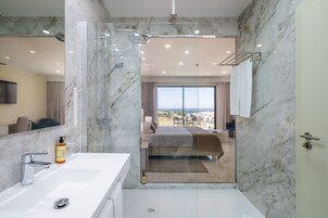 A modern bathroom with a glass-enclosed shower, a white sink, and a large mirror.