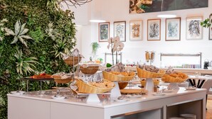Un buffet composé de paniers en osier remplis de nourriture, d’une variété d’assiettes et d’un mur décoré de plantes et d’œuvres d’art encadrées.