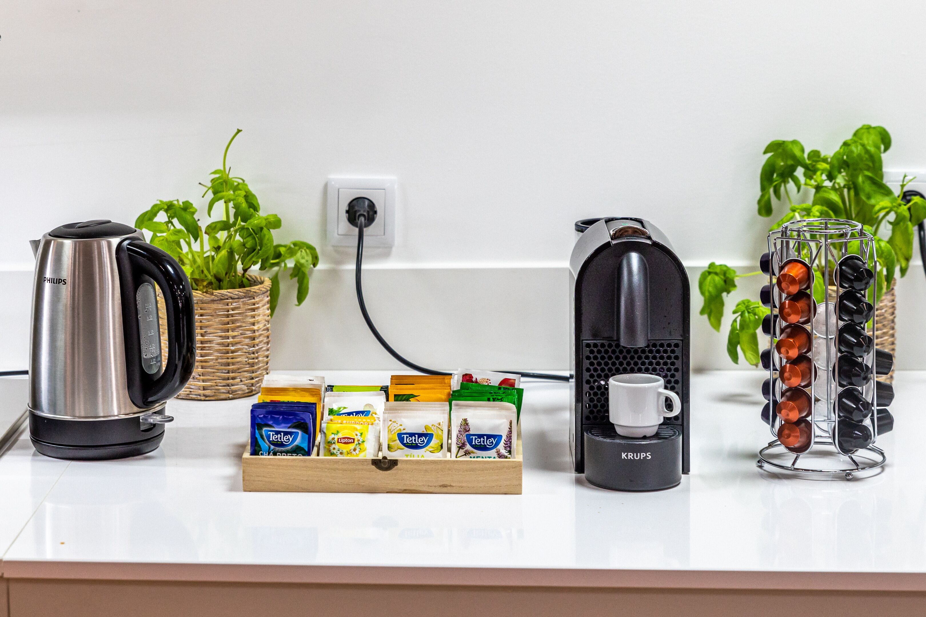 A kitchen counter with a coffee maker, a kettle, a coffee mug, and a spice rack.