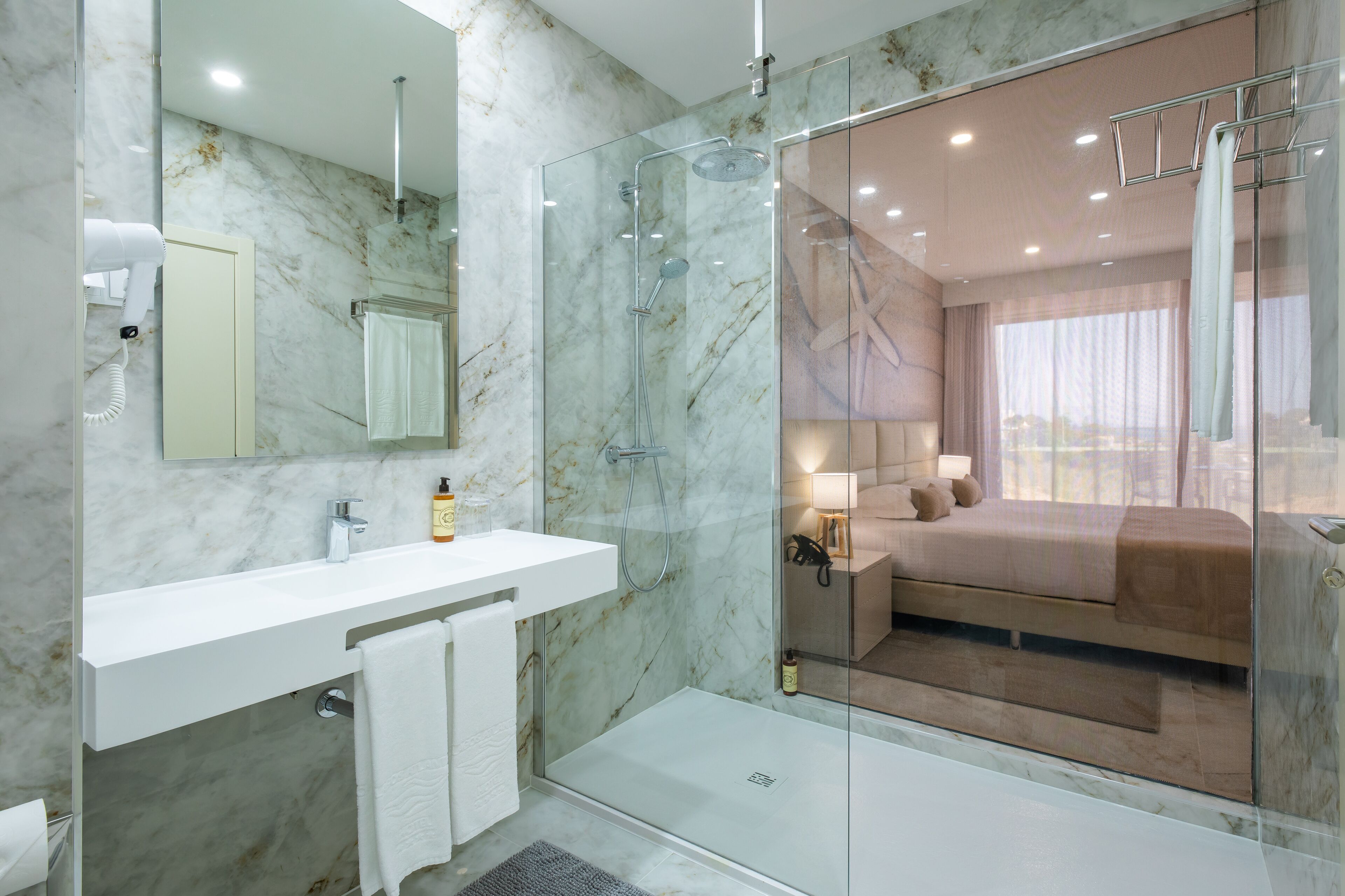A modern bathroom with a glass shower enclosure, a white sink, and a large mirror.