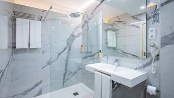A modern bathroom with a glass-enclosed shower, a white sink, and a marble backsplash.