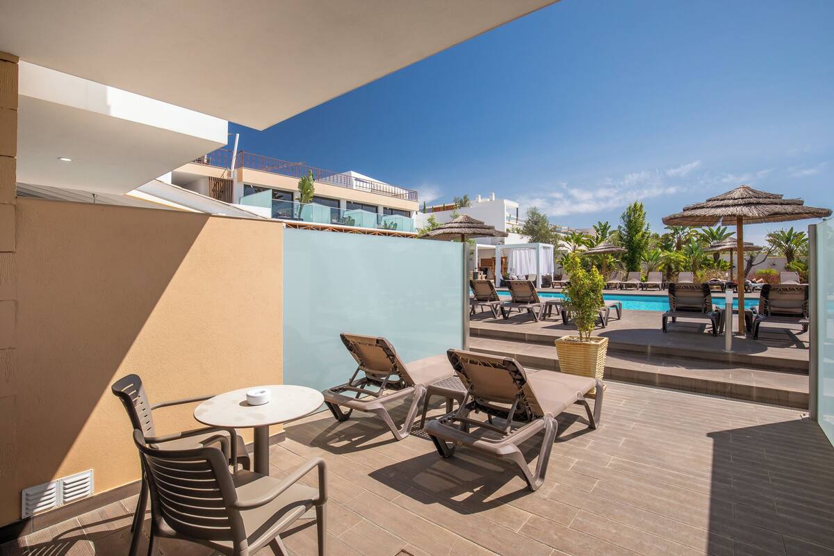 A rooftop pool area with lounge chairs, a table, and umbrellas.