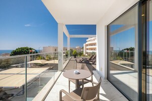 A modern balcony with a glass railing, a round table, and two chairs.