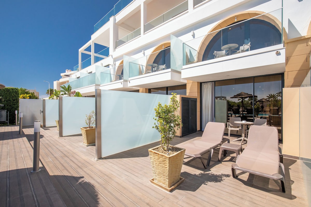 A modern hotel with outdoor seating, a pool, and a covered area with a view of the pool.