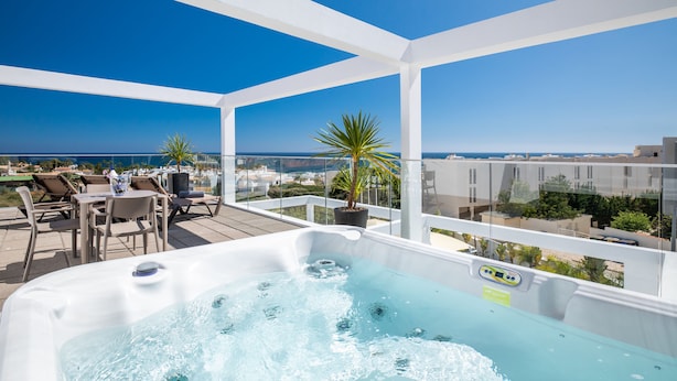 Une terrasse sur le toit avec un jacuzzi, un espace salon et une vue sur l’océan.