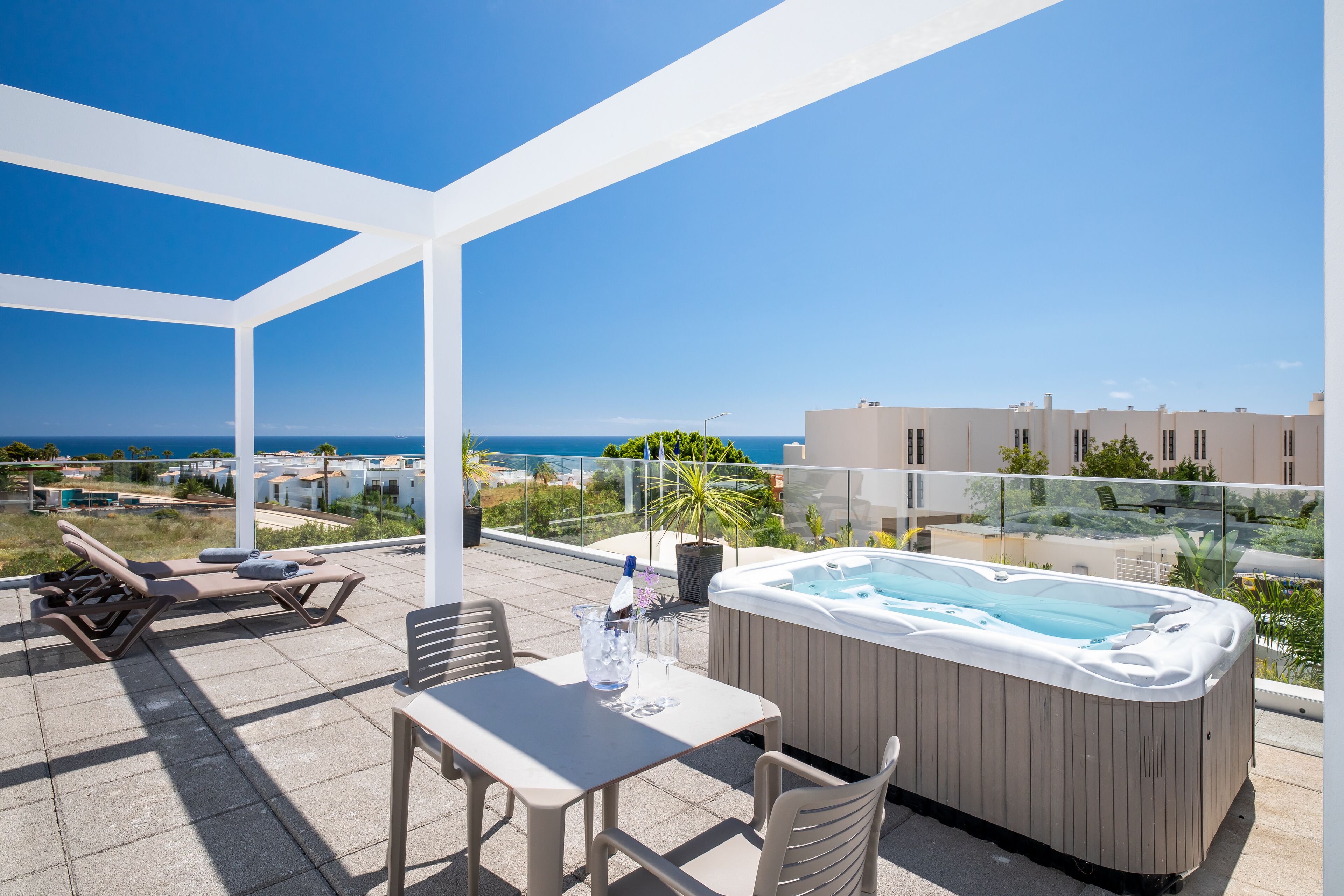 Une terrasse sur le toit équipée d’un jacuzzi, de chaises longues et d’une table.