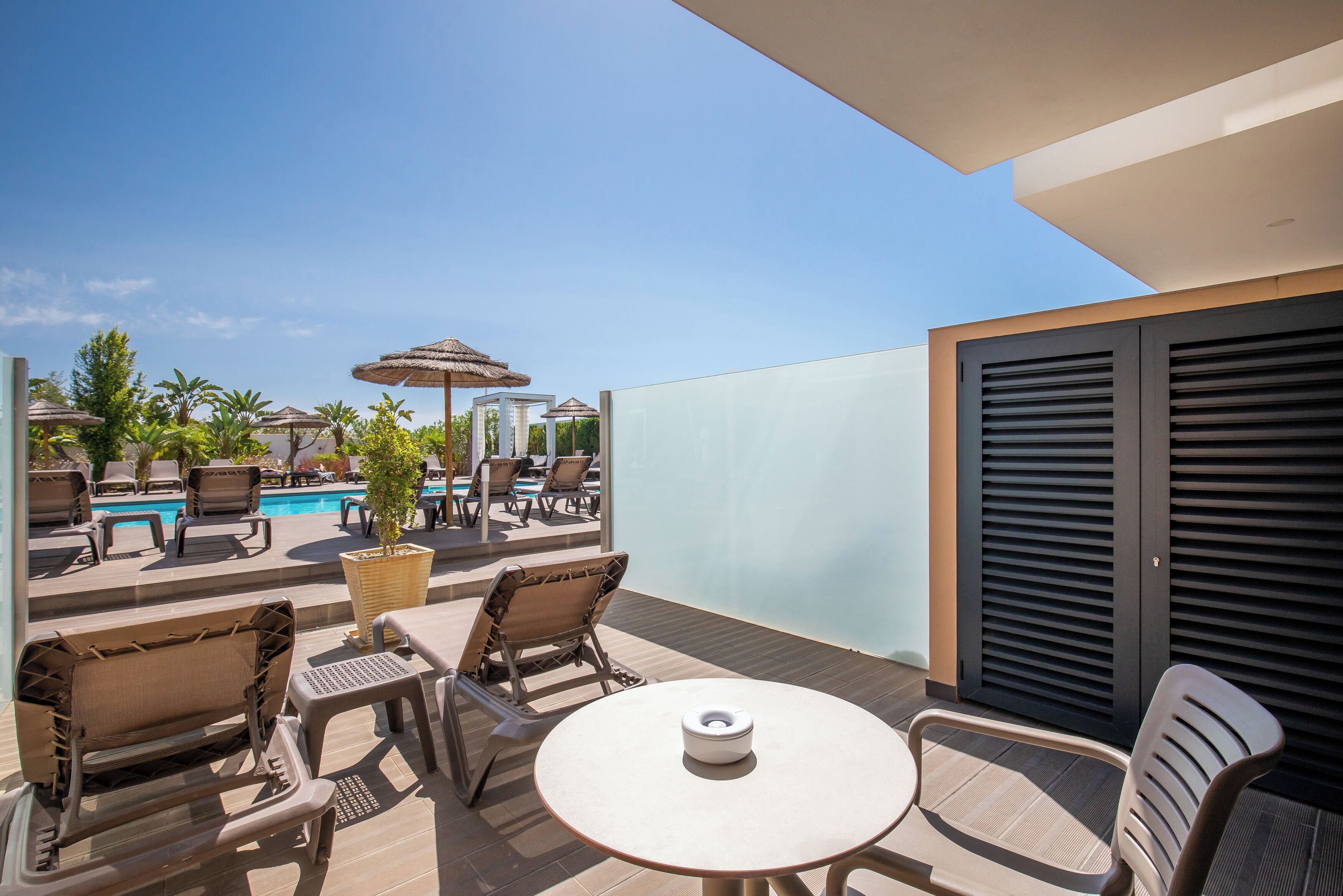 A balcony with outdoor seating, a pool, and a view of the sky.