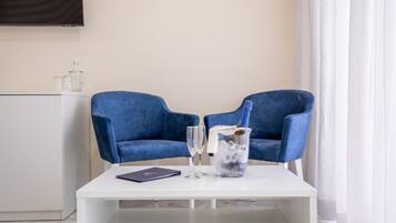 Una habitación moderna con dos sillas azules, una mesa blanca y un minibar.
