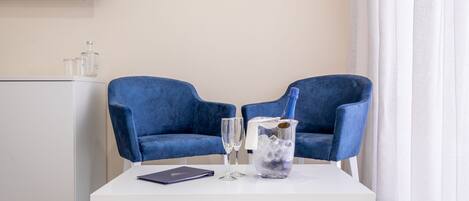 Una habitación moderna con dos sillas azules, una mesa blanca y un minibar.