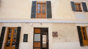A building with a wooden door, a balcony with a metal railing, and a sign on the wall. - My Rooms Arta - Adults Only by My Rooms Hotels (Arta)