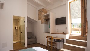 A bedroom with a bed, a desk, a chair, a TV, and a staircase. - My Rooms Arta - Adults Only by My Rooms Hotels (Arta)