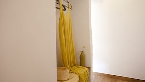 A room with a wooden floor, a yellow curtain, a hat, and a vase on a shelf. - My Rooms Arta - Adults Only by My Rooms Hotels (Arta)