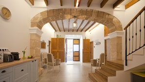 A spacious kitchen with a stone archway, wooden staircase, and a view to a dining area. - My Rooms Arta - Adults Only by My Rooms Hotels (Arta)
