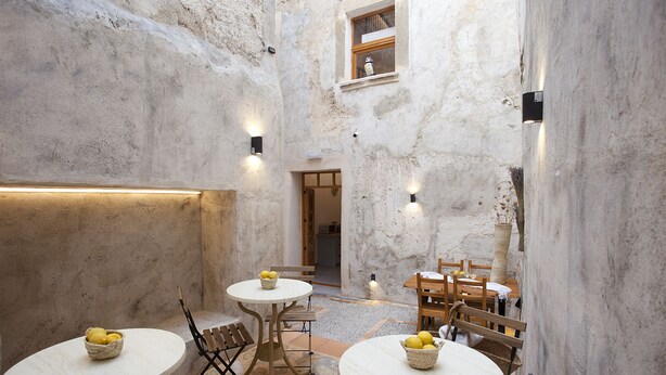 A rustic interior with stone walls, two round tables with baskets of lemons, and wooden chairs. - My Rooms Arta - Adults Only by My Rooms Hotels (Arta)