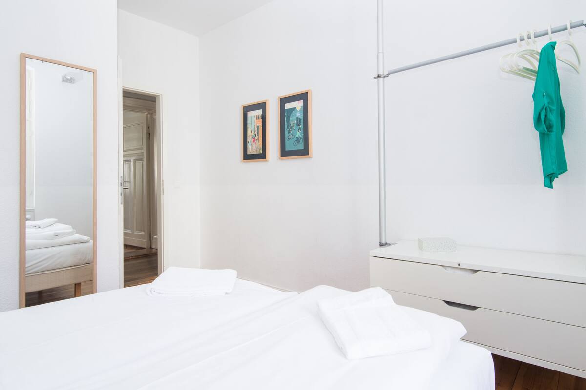 Ein Hotelzimmer mit einem Bett, einem Spiegel, einer weißen Kommode und zwei gerahmten Bildern an der Wand.