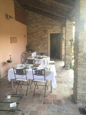 An outdoor dining area with stone walls and a brick floor, featuring tables set for a meal. - Canonica dei Templari (Camino)