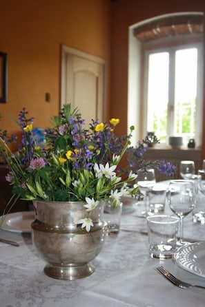 A dining table set with a silver bowl containing a floral arrangement, glasses, and cutlery. - Canonica dei Templari (Camino)