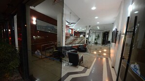 Un vestíbulo de hotel con una recepción, una zona de estar y una escalera que lleva a los pisos superiores.