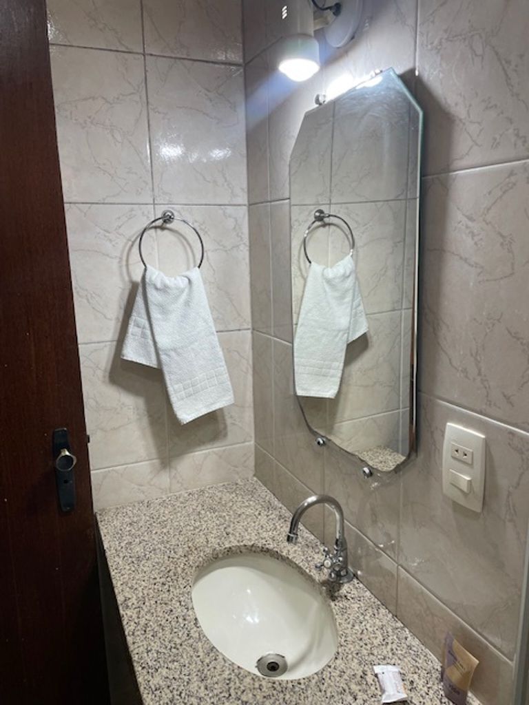 Un baño con lavamanos, dos toalleros, un espejo y una puerta.