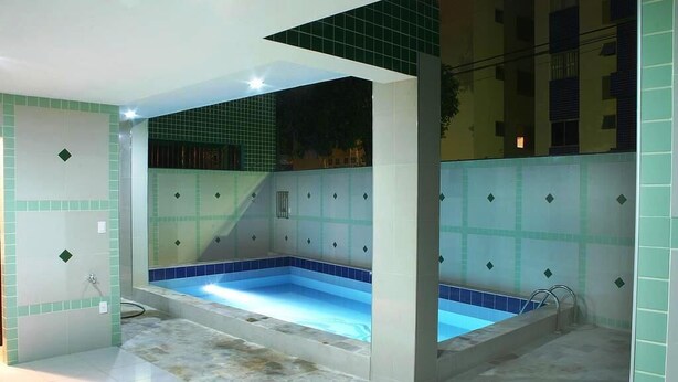 Un área de spa con una bañera de hidromasaje, paredes y suelo de azulejos.