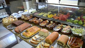 Un bufé con diferentes opciones de comida, como pan, pasteles, frutas y verduras.