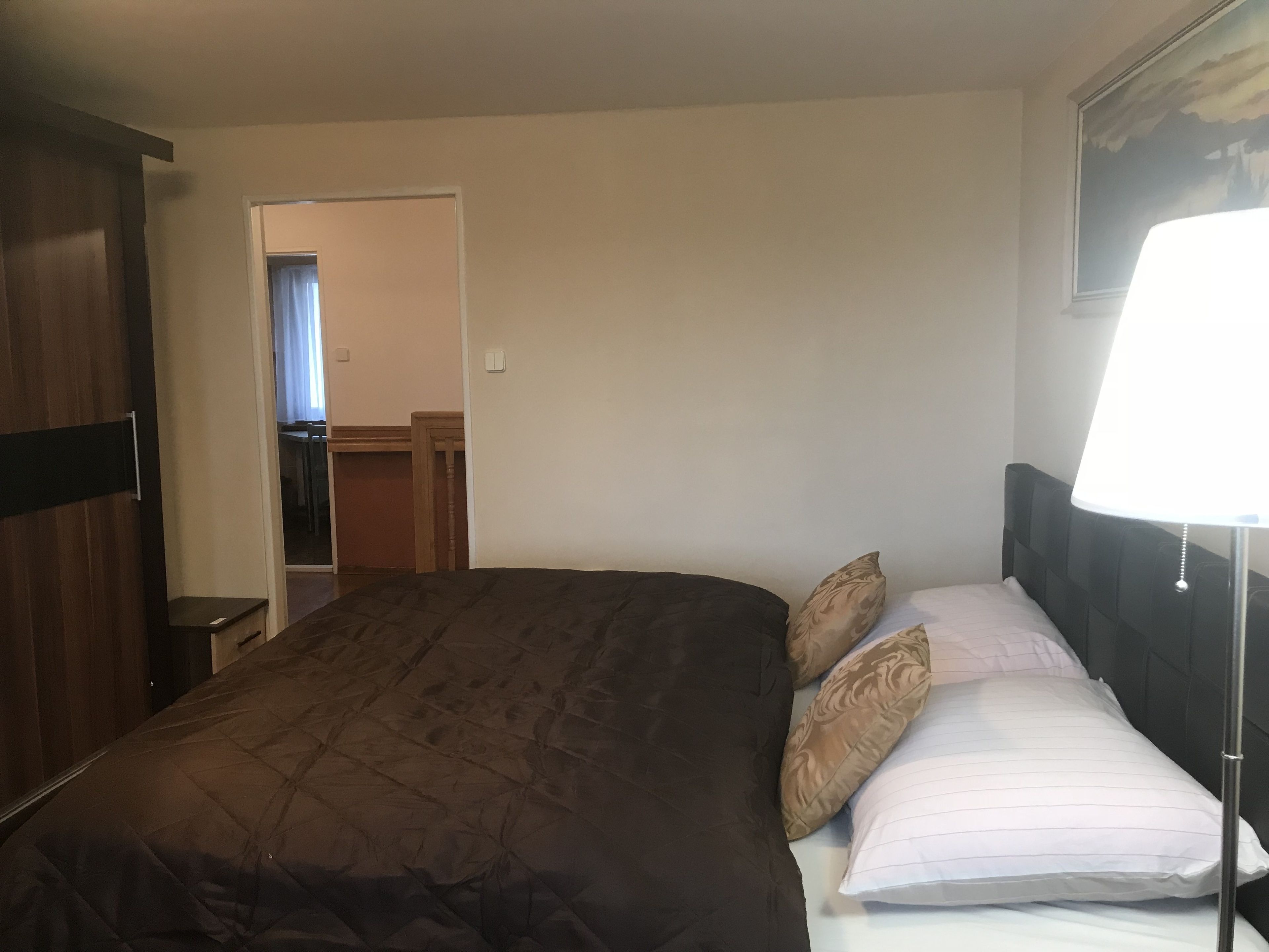 Een hotelkamer met een groot bed, een bedlampje en een deur naar een badkamer.