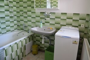 A bathroom with a white sink, a bathtub, and a washing machine. - Apartment pod Lysou 3 Bedroom (Frydlant nad Ostravici)