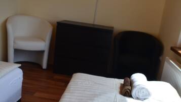 Une chambre d’hôtel avec un lit, une chaise, une petite table et un téléviseur fixé au mur.