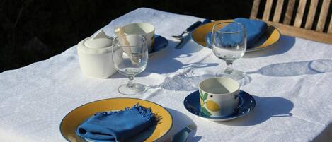 A table set outdoors with a white tablecloth, blue napkins, and yellow plates.