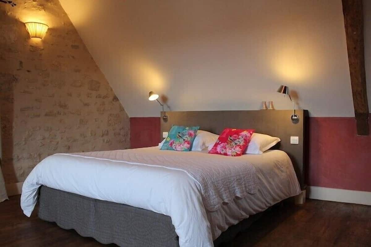A bedroom with a bed, two wall-mounted lamps, and a stone wall.