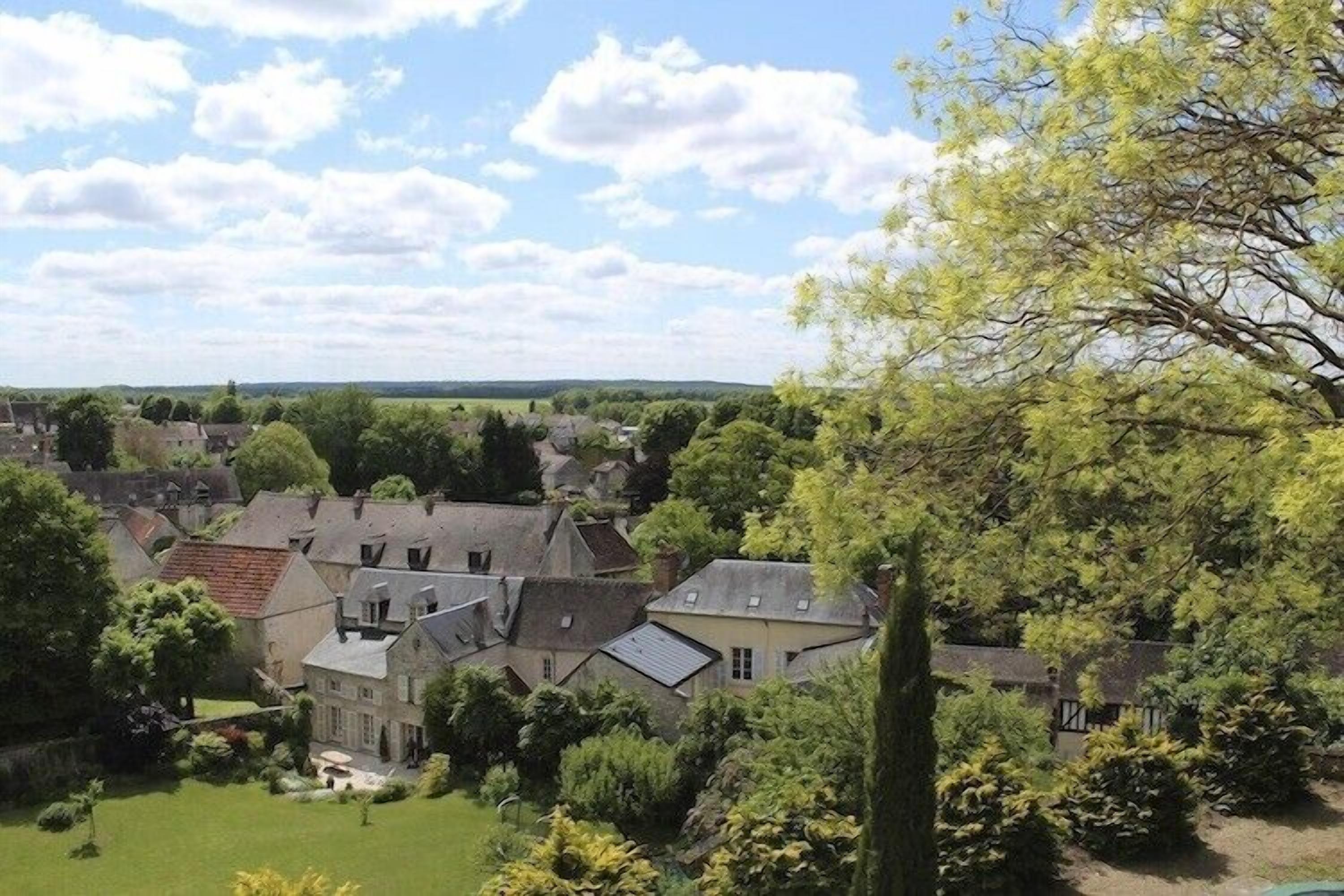A rural village with traditional stone houses, a large tree in the foreground, and a clear sky.