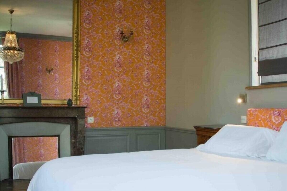 A hotel room with a large bed, a fireplace, and a chandelier.