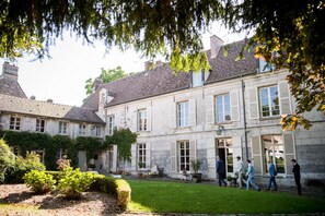 A historic stone building with a courtyard, large windows, and a well-maintained garden. - Chambres d'Hôtes de Parseval (Senlis)