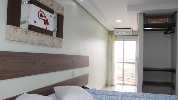 A hotel room with a bed, a headboard, a mirror, a wardrobe, and a sliding glass door to the outside. - Hotel Soldera Inn (Sertaozinho)