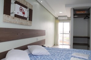 Ein Hotelzimmer mit einem Bett, einem Kopfteil, einem Spiegel, einem Kleiderschrank und einer Schiebeglastür zum Außenbereich.