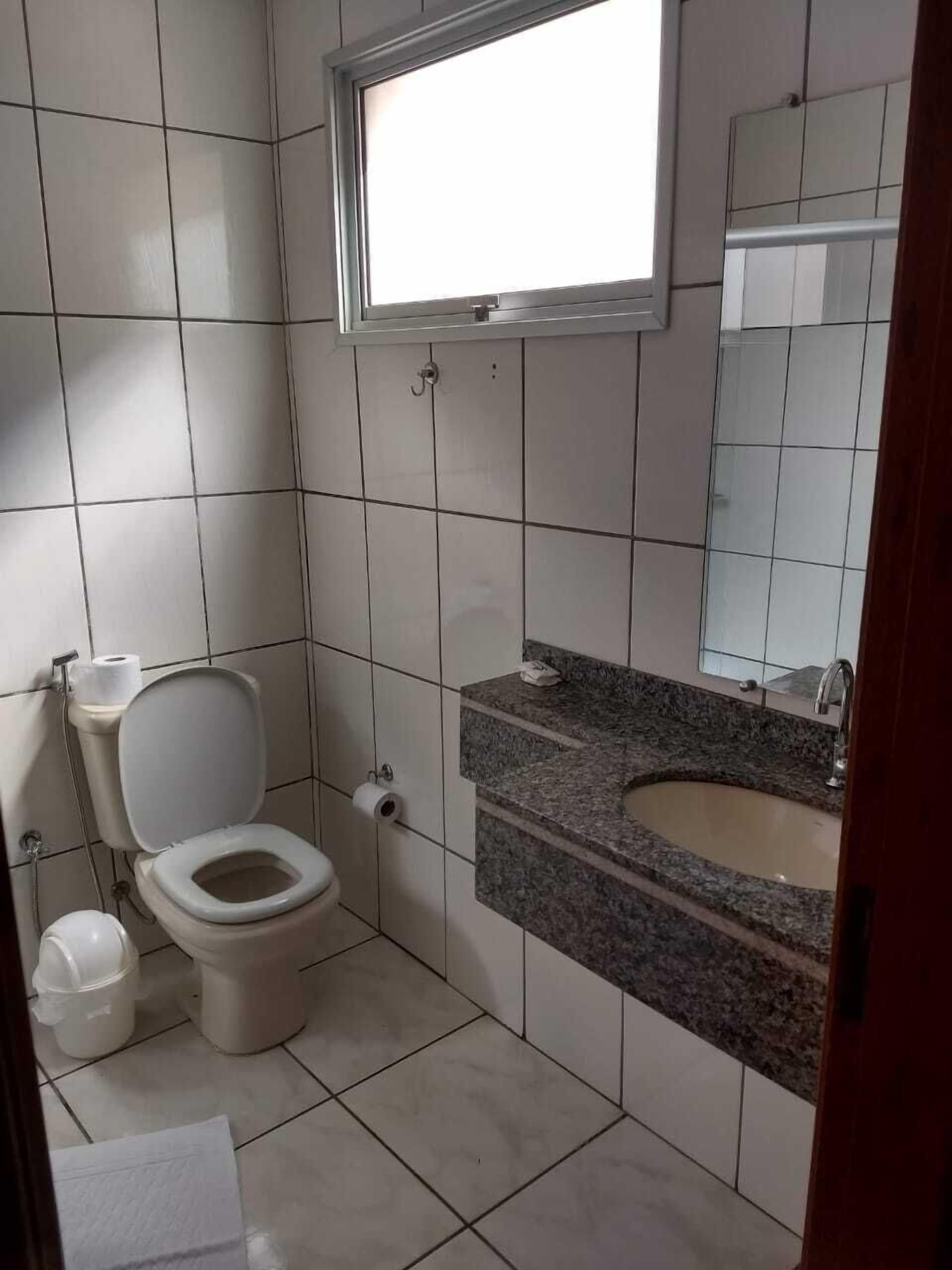 A small bathroom with a toilet, sink, and a mirror.