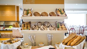 A buffet counter with various breads and pastries displayed on shelves and baskets. - HL Suites Nardos - Only Adults (San Bartolomé de Tirajana)