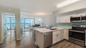 Una cocina moderna con electrodomésticos de acero inoxidable, un comedor con vistas y una sala de estar amplia.