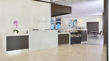 A reception area with a modern design, featuring a reception desk, a seating area, and a counter with amenities.