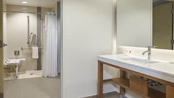 Un baño moderno con un lavamanos blanco, tocador de madera y un espejo grande.