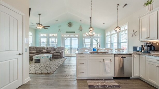 Cocina amplia con una isla central, armarios blancos y vistas al exterior.