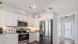 Una cocina moderna con armarios blancos, electrodomésticos de acero inoxidable y piso de madera.