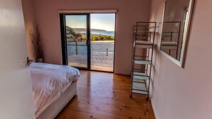 Ein Schlafzimmer mit einem Bett, einer Glasschiebetür, die zu einem Balkon führt, und einem Metallregal.