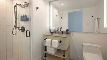 A modern bathroom with a shower, toilet, sink, and towel rack.