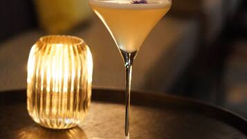 Una copa de martini sobre una mesa redonda con una vela al fondo.