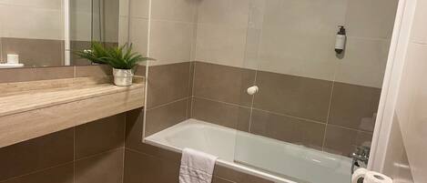 A modern bathroom with a bathtub, toilet, and sink.