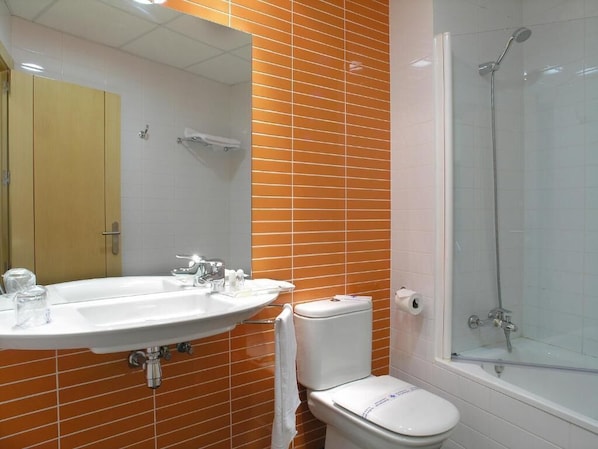 Un baño con un lavamanos blanco, un inodoro y una ducha con mampara de vidrio.